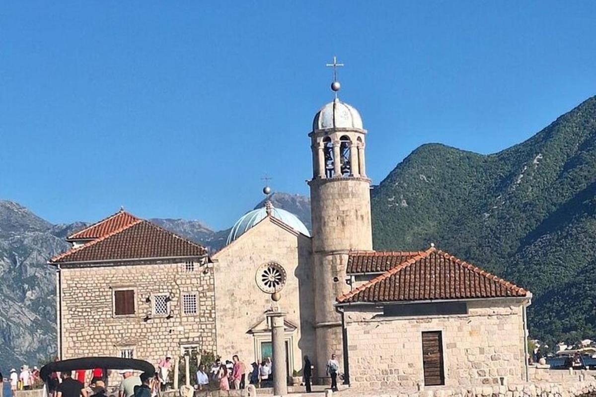 uma igreja com uma torre do relógio em frente às montanhas