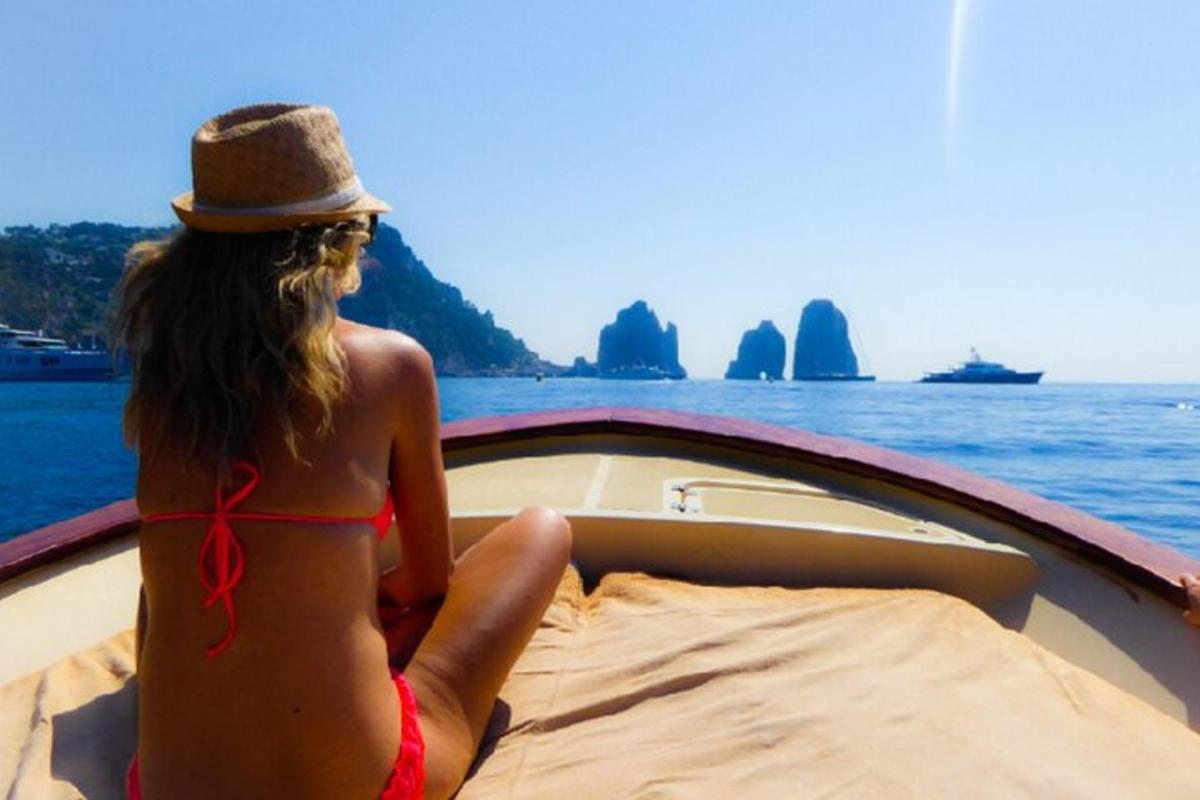Una mujer en bikini sentada en la parte delantera de un barco.