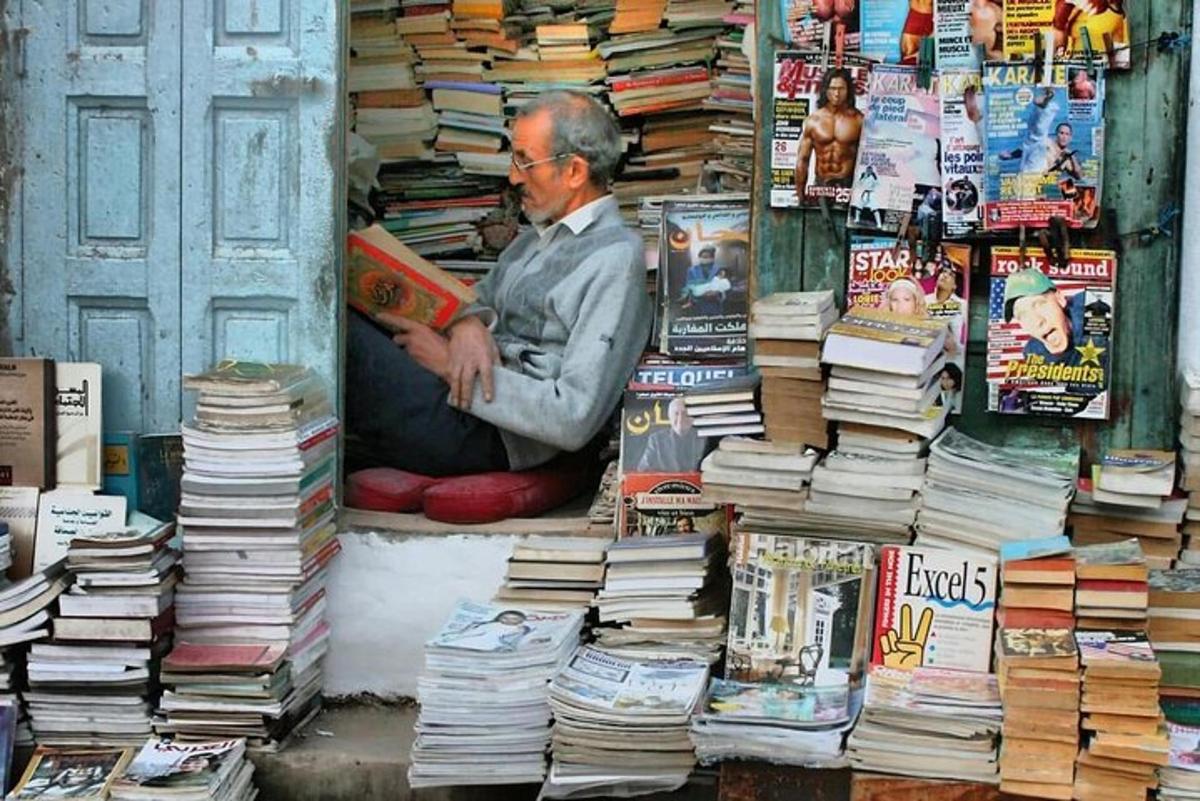 a man reading a book in front of a pile of books