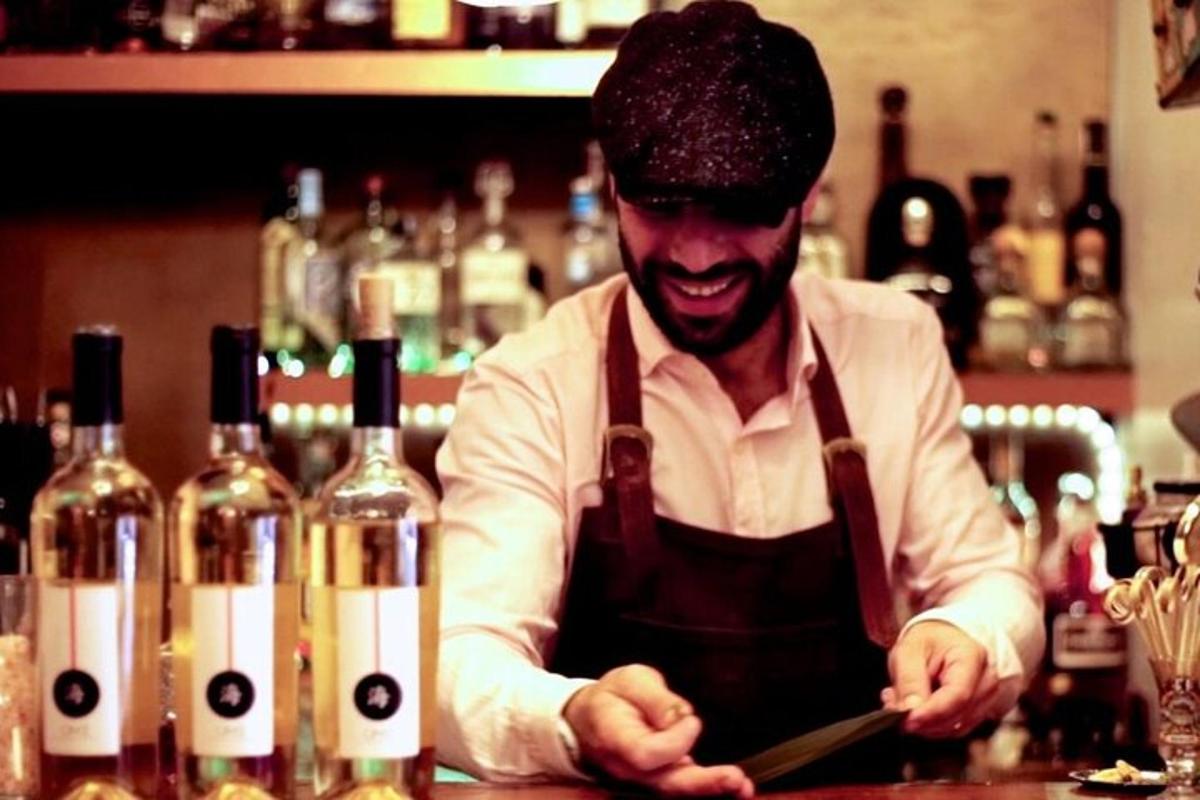 un uomo in piedi dietro un bar con bottiglie di vino