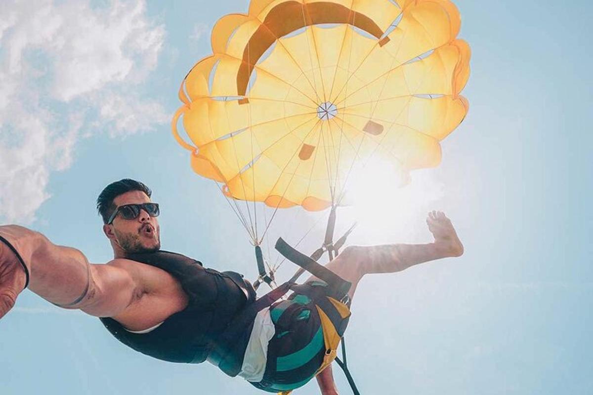 een man die met een parachute door de lucht vliegt