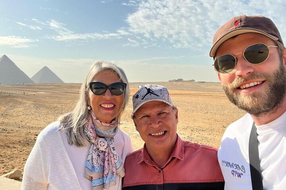 three people posing for a picture in front of the pyramids