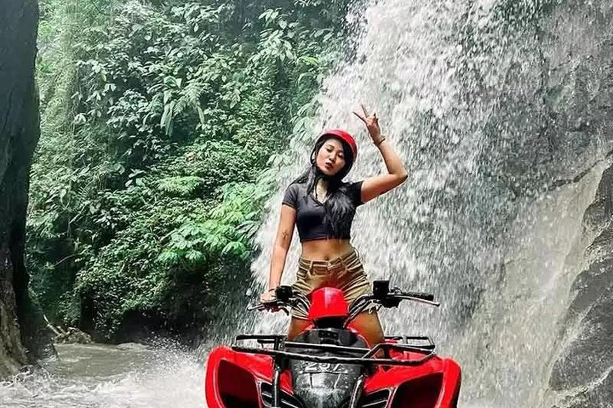 žena jedoucí na motorce před vodopádem