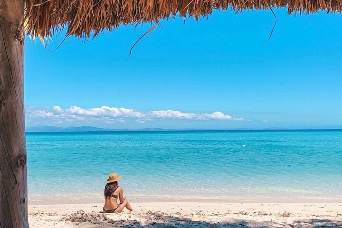 a woman sitting on a beach looking at the ocean