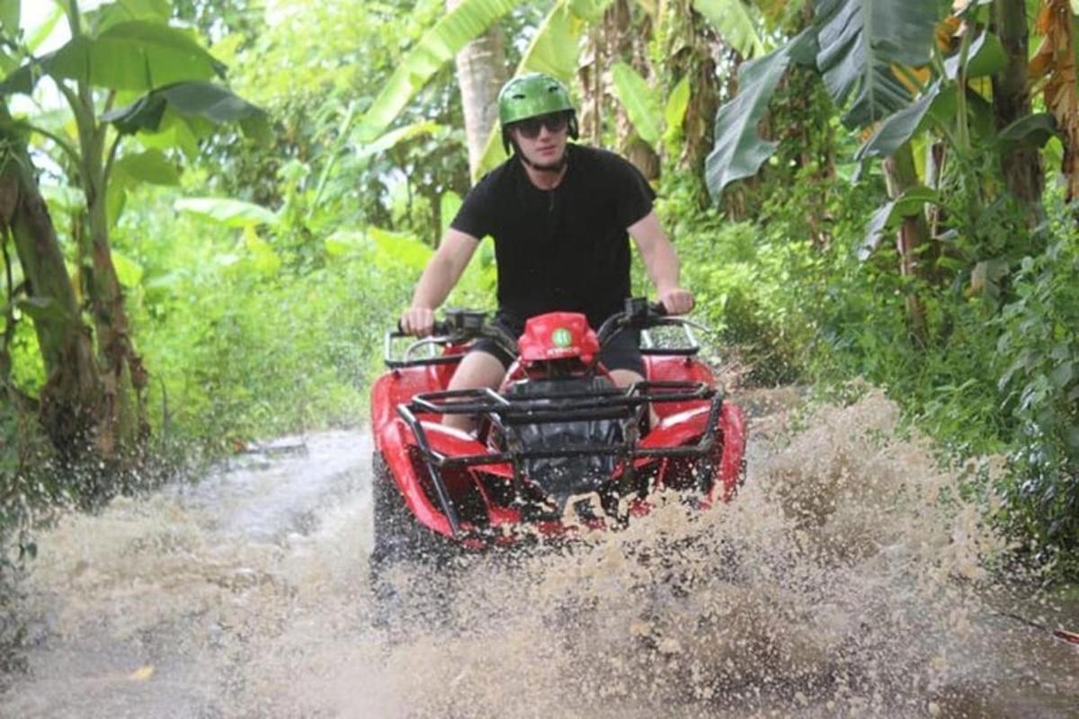 Un hombre conduciendo un vehículo de cuatro ruedas por el agua.