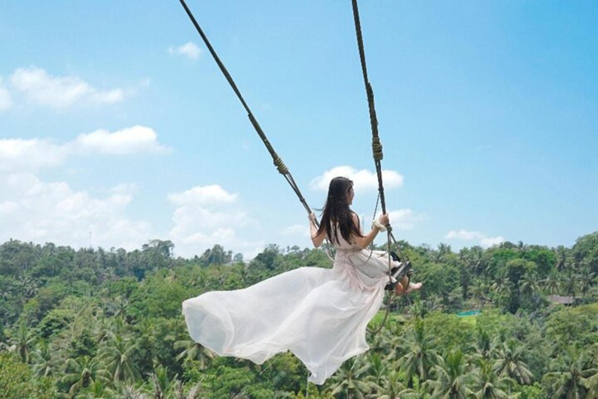 una dona amb un vestit blanc balancejant-se en un gronxador de corda