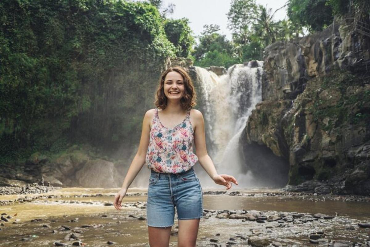 uma mulher parada em frente a uma cachoeira