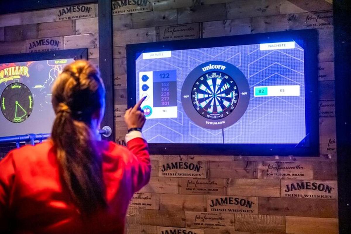 o femeie care arată spre o tablă de darts pe un perete