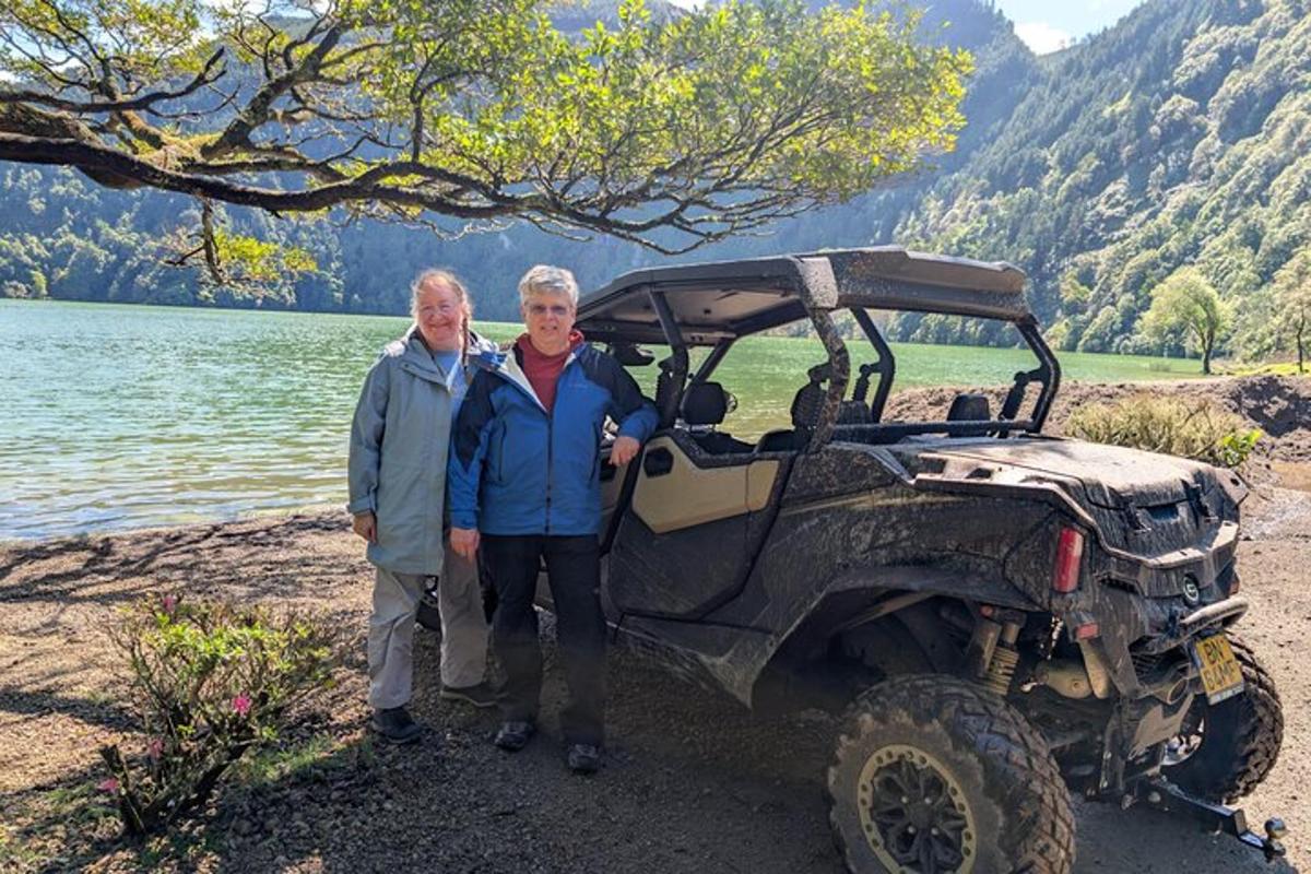 two older women standing next to a jeep next to a lake