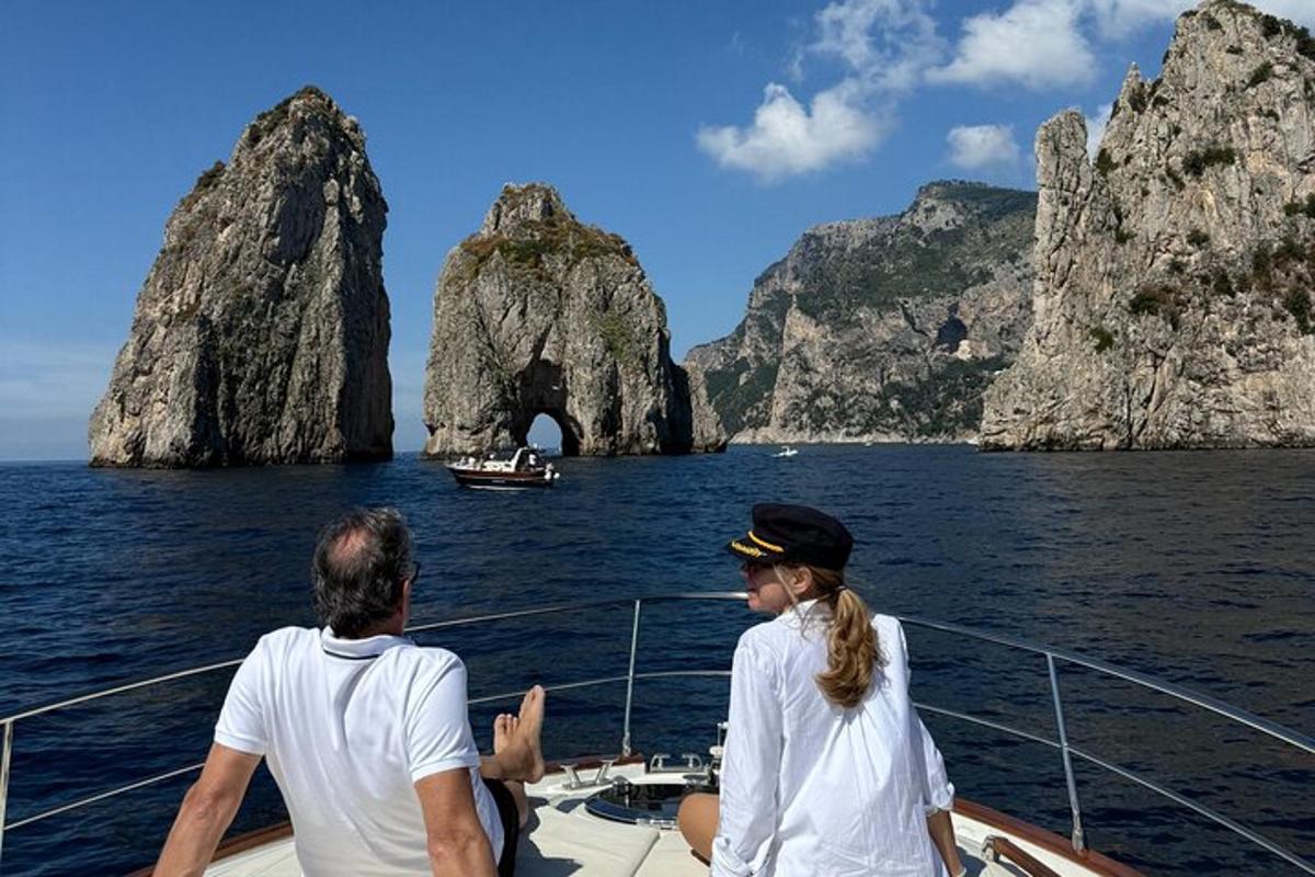 Dos personas en un barco frente a una cueva en el agua.