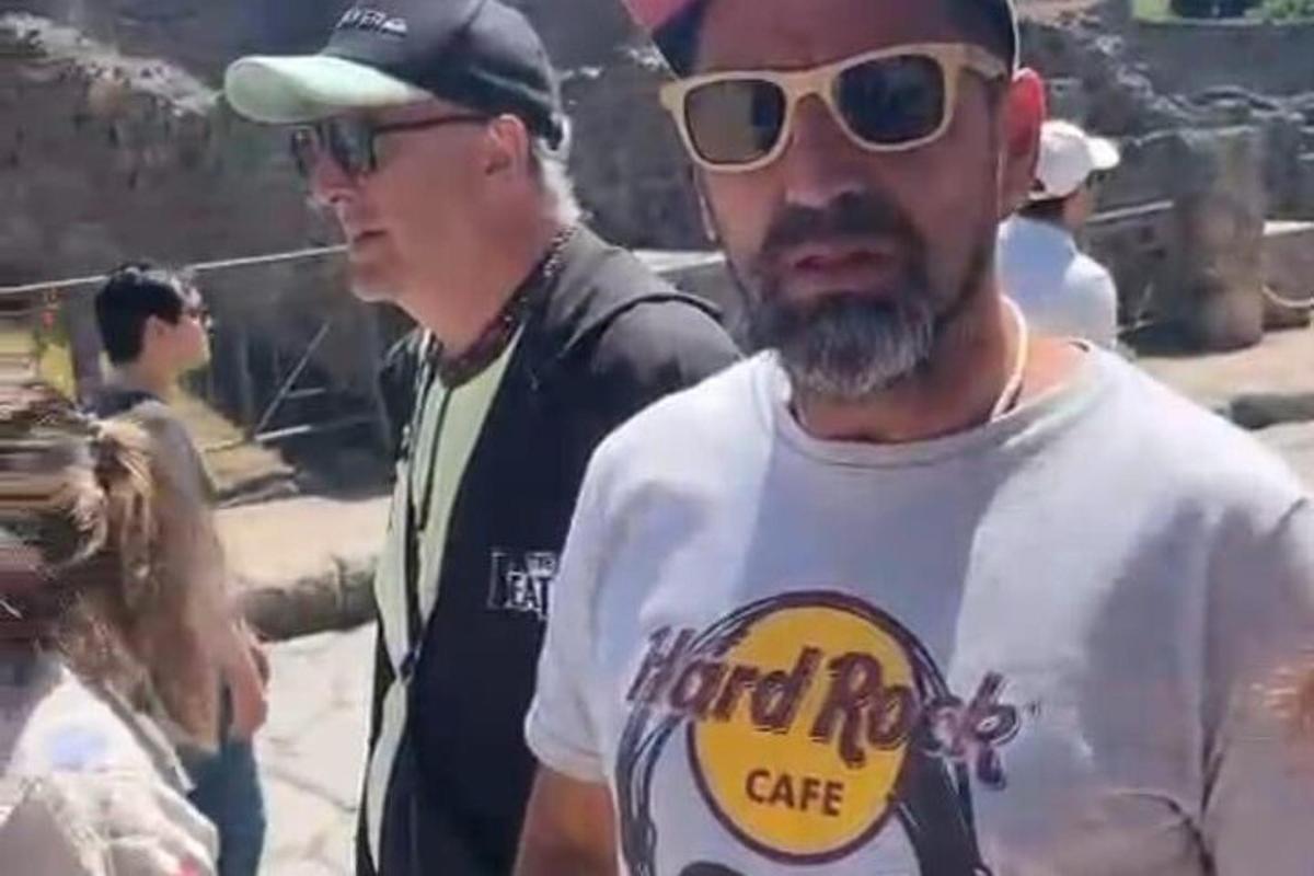 Ein Mann mit Hut und Sonnenbrille steht neben einem anderen Mann