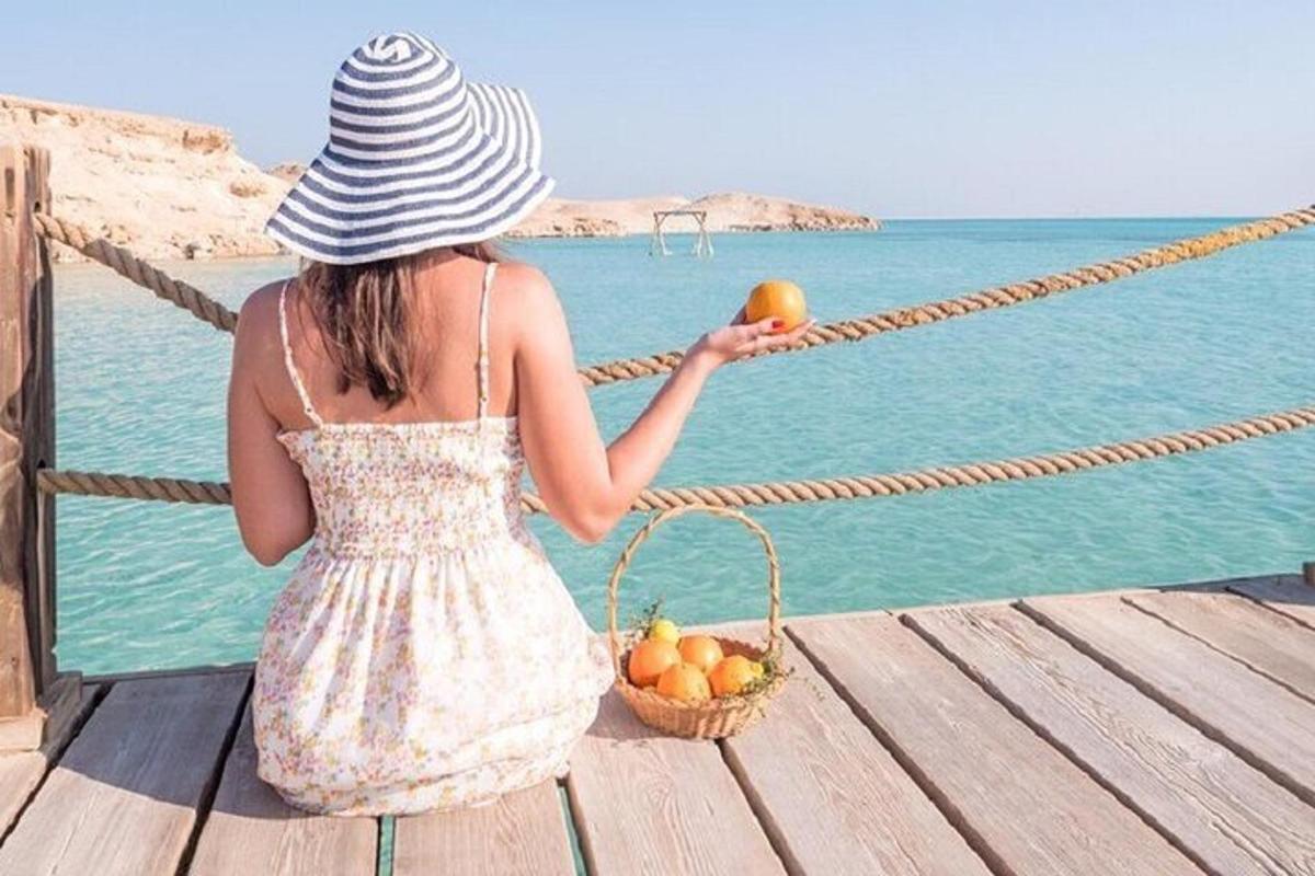 a young girl sitting on a dock with a basket of fruit