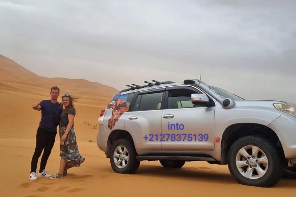 رجل وامرأة يقفان بجوار سيارة رياضية متعددة الاستخدامات في الصحراء