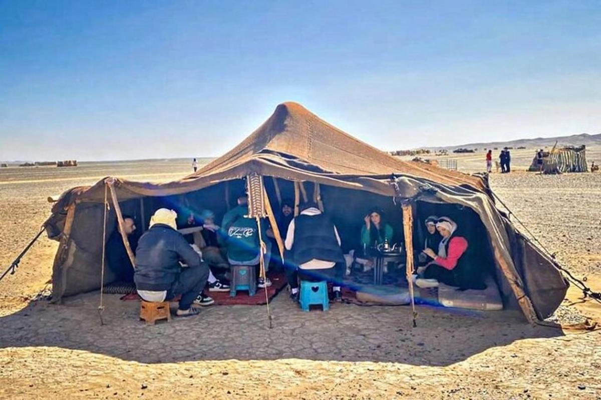 مجموعة من الناس يجلسون في خيمة في الصحراء