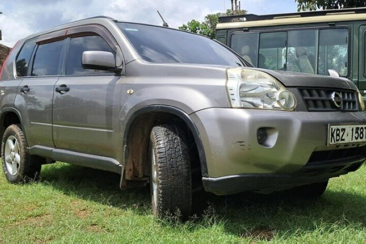 sebuah trak kelabu diletakkan di rumput di sebelah bas
