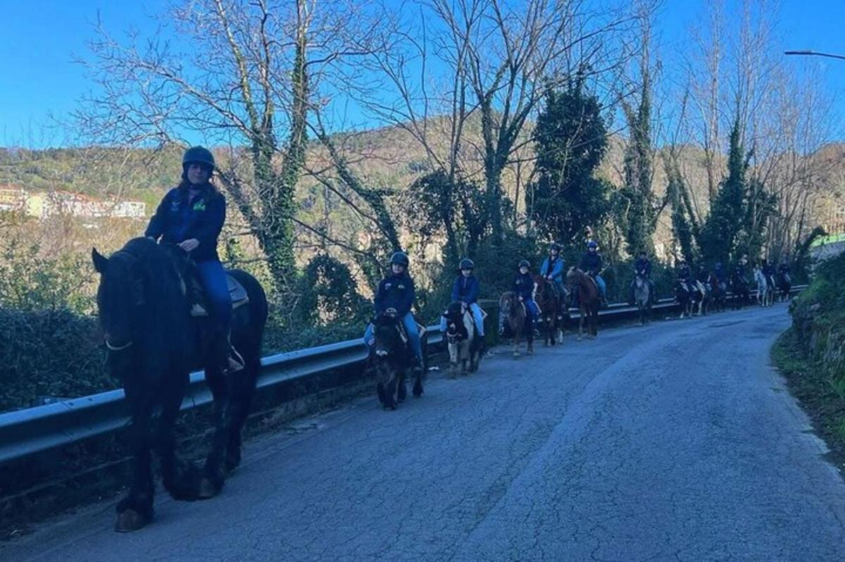 μια ομάδα ανθρώπων που καβαλούν άλογα σε έναν δρόμο
