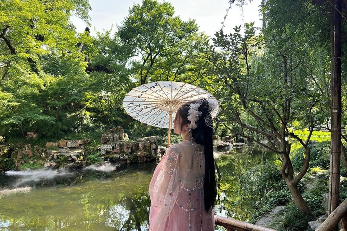 a woman in a dress holding an umbrella near a pond
