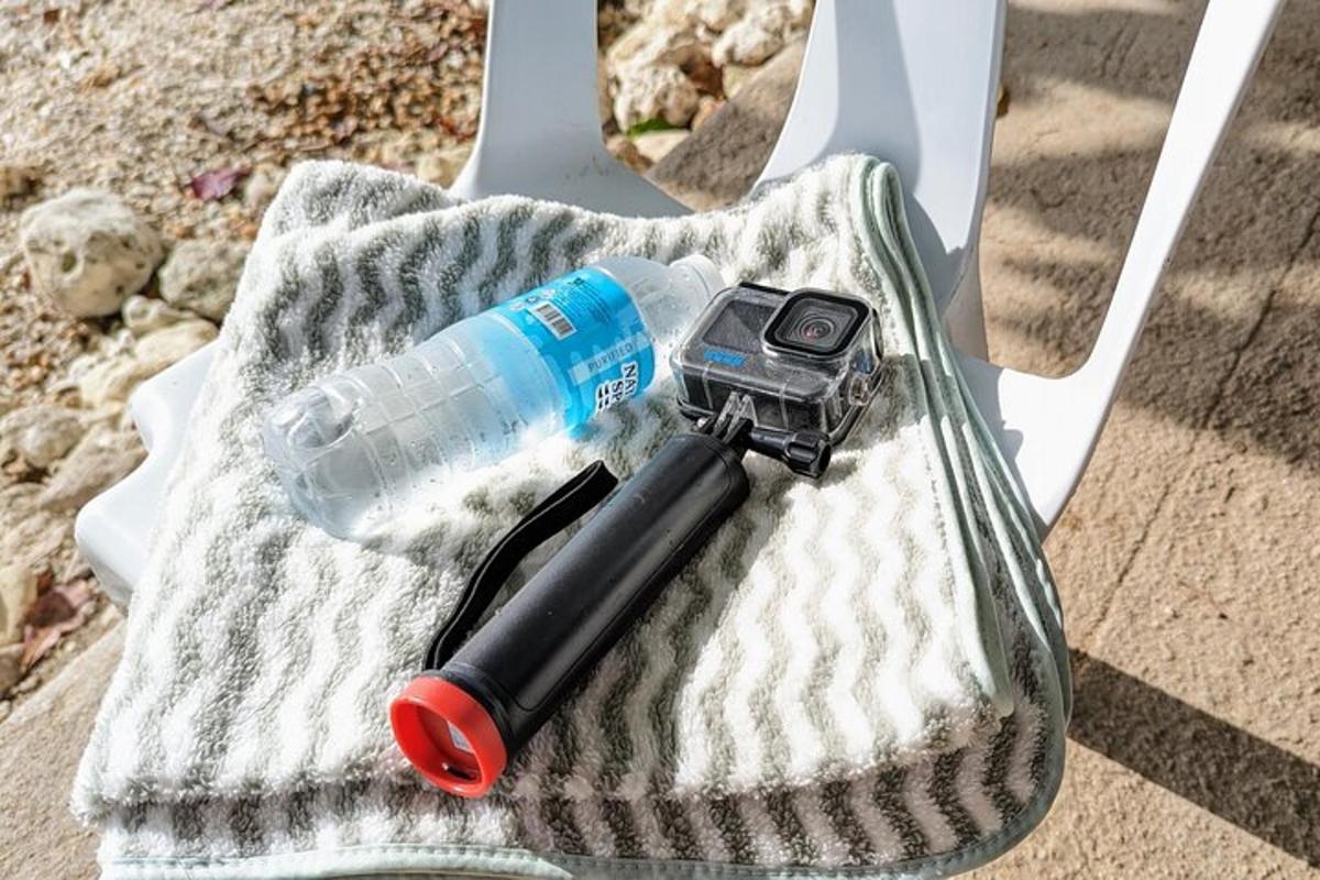una bottiglia d'acqua, una macchina fotografica e una penna su un asciugamano