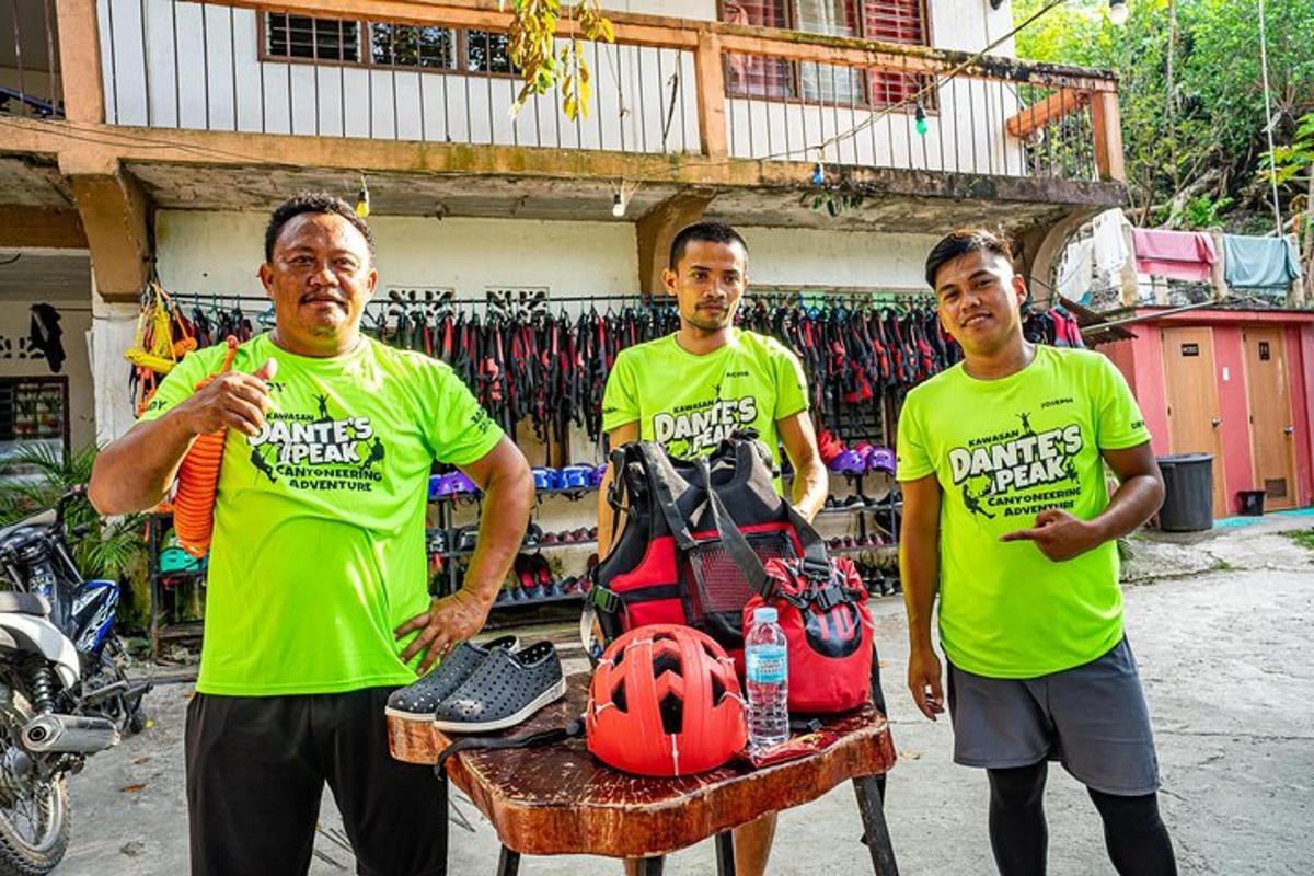 três homens de camisa verde em pé ao lado de uma mesa com um capacete