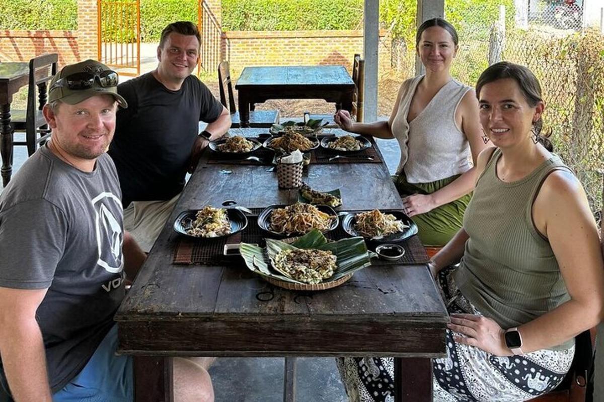 a group of people sitting around a wooden table with food