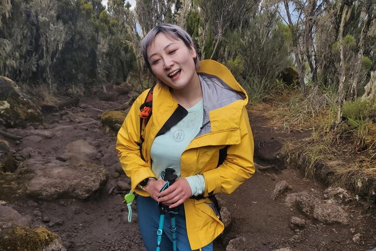 a woman in a yellow jacket standing on a trail