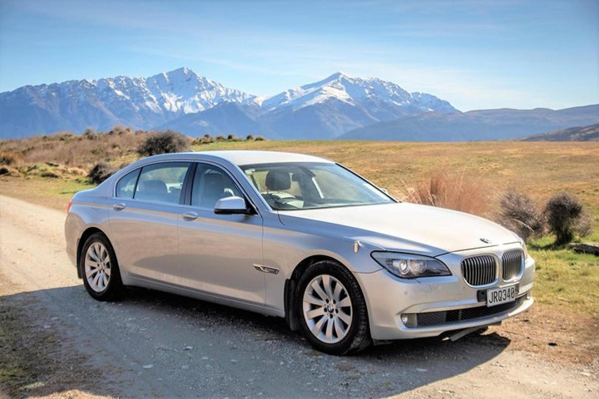 a silver car parked on a road with mountains in the background