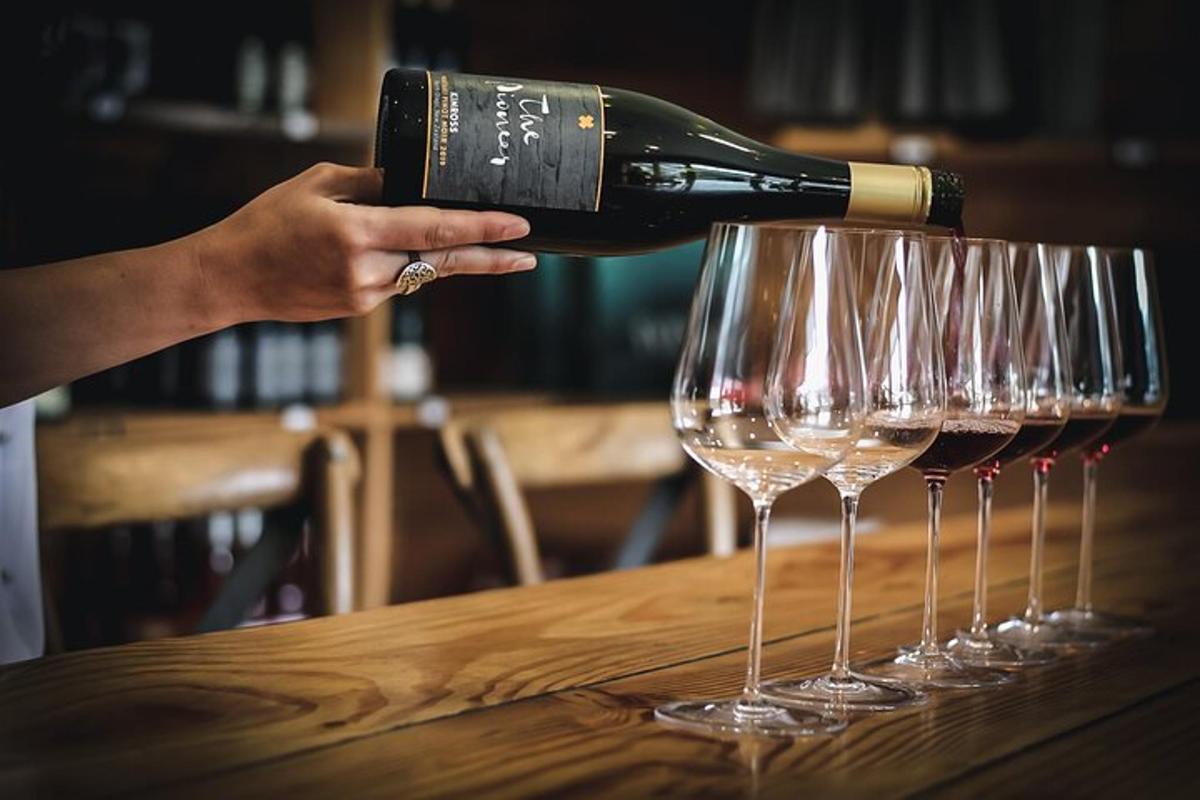 a person pouring a bottle of wine into four wine glasses