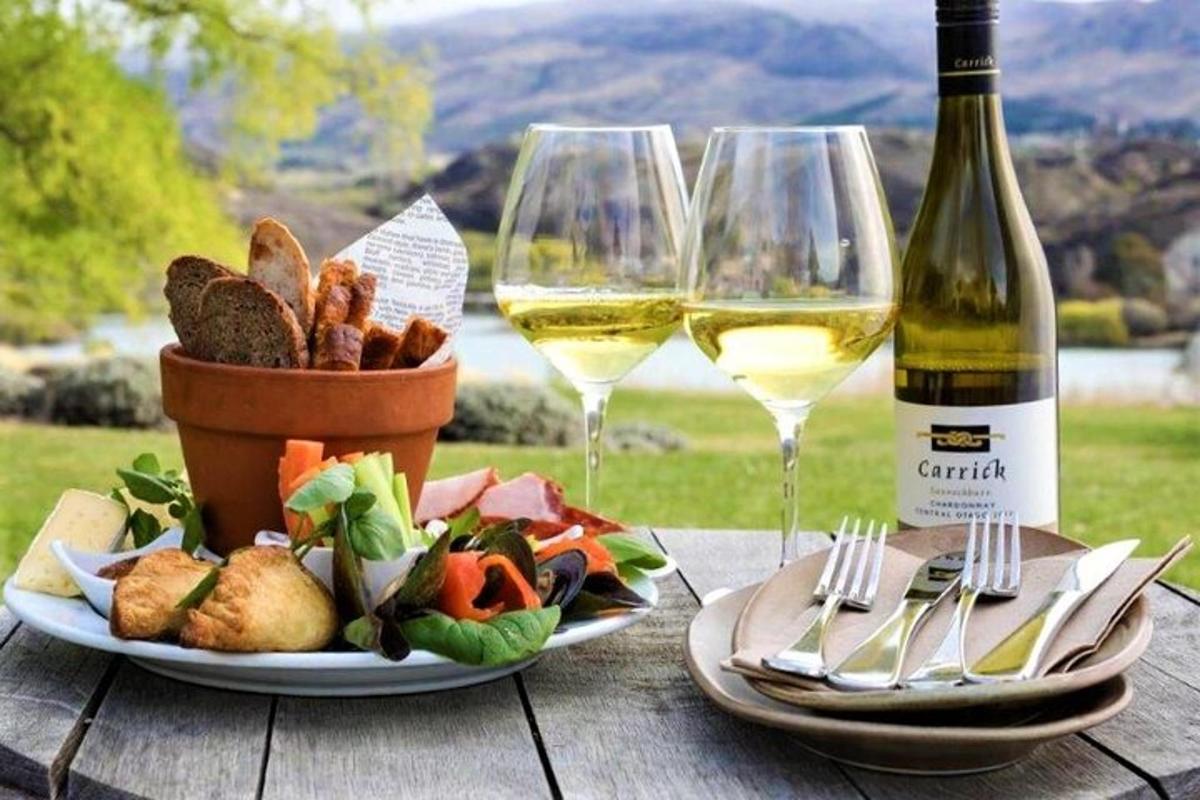 a table with two glasses of wine and a basket of food