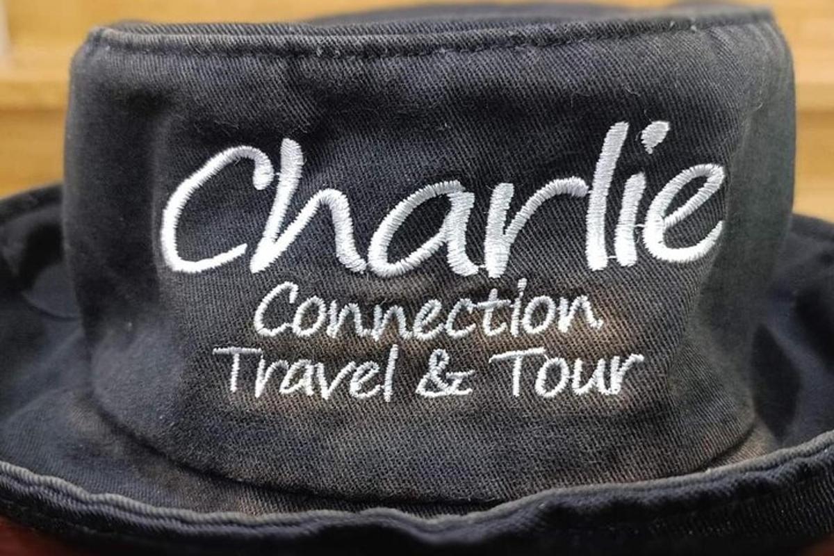 o pălărie neagră cu cuvintele charma communication travel and tour