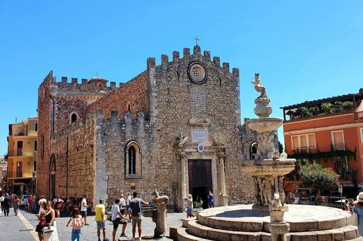 um antigo edifício de pedra com uma torre do relógio e uma fonte