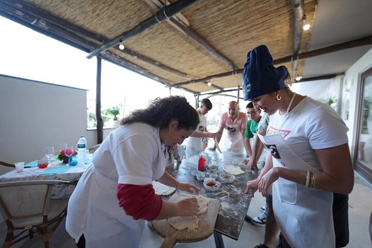 sieviešu grupa, kas stāv ap galdu un gatavo ēdienu