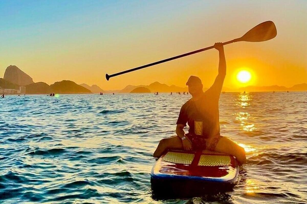 osoba na paddleboardu ve vodě při západu slunce