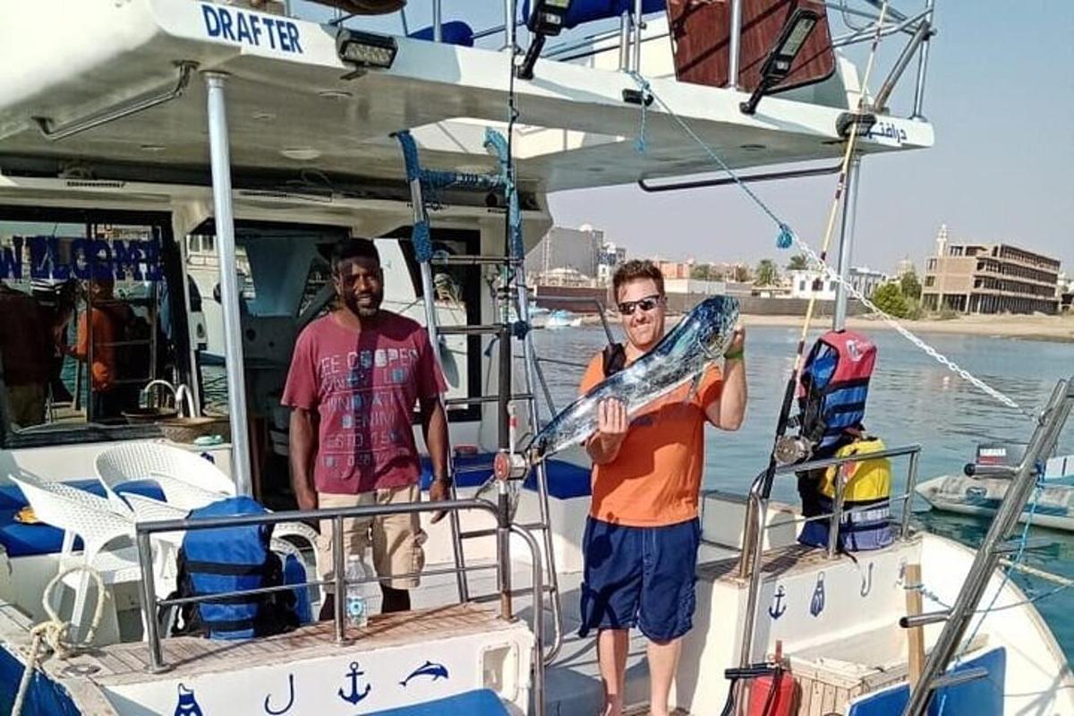 two men standing on a boat with a surfboard