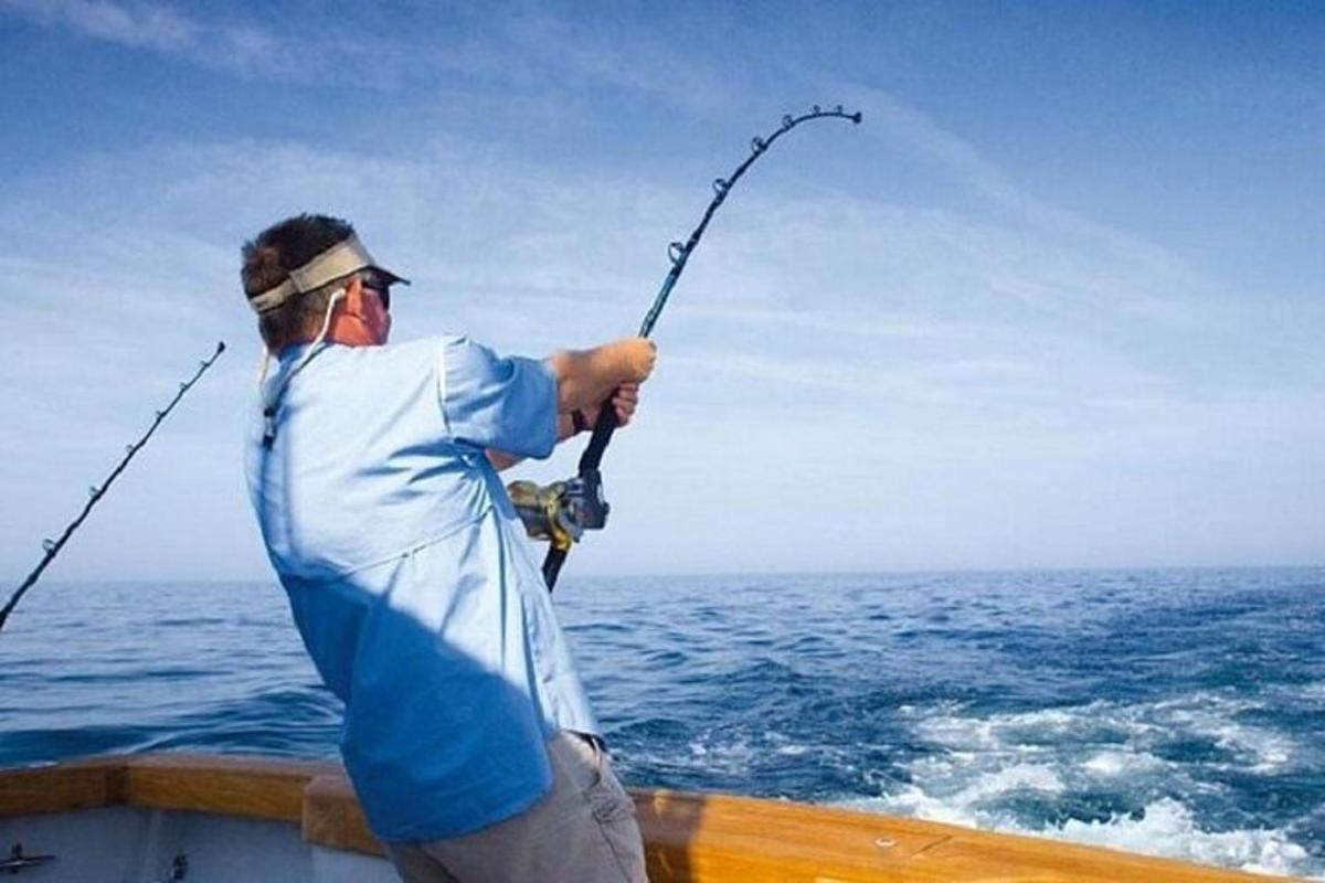 a man holding a fishing rod on a boat in the ocean