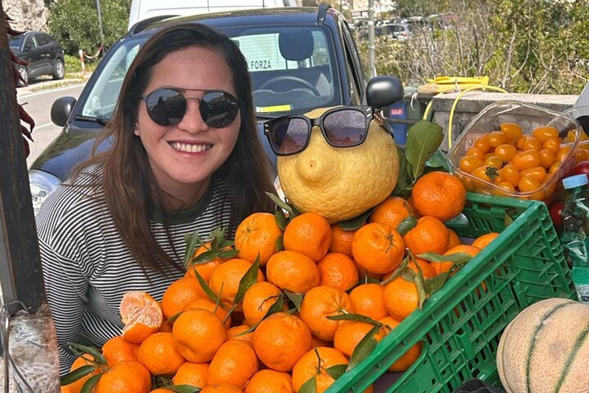 nakangiting babae sa tabi ng isang crate ng oranges