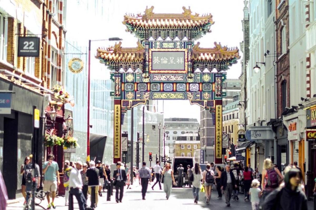 Una multitud de personas caminando por una calle con una puerta china.
