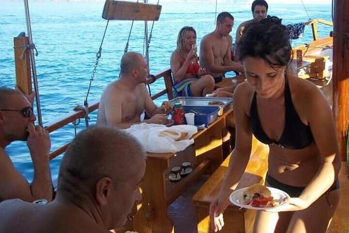 seorang wanita memegang sepiring makanan di atas perahu