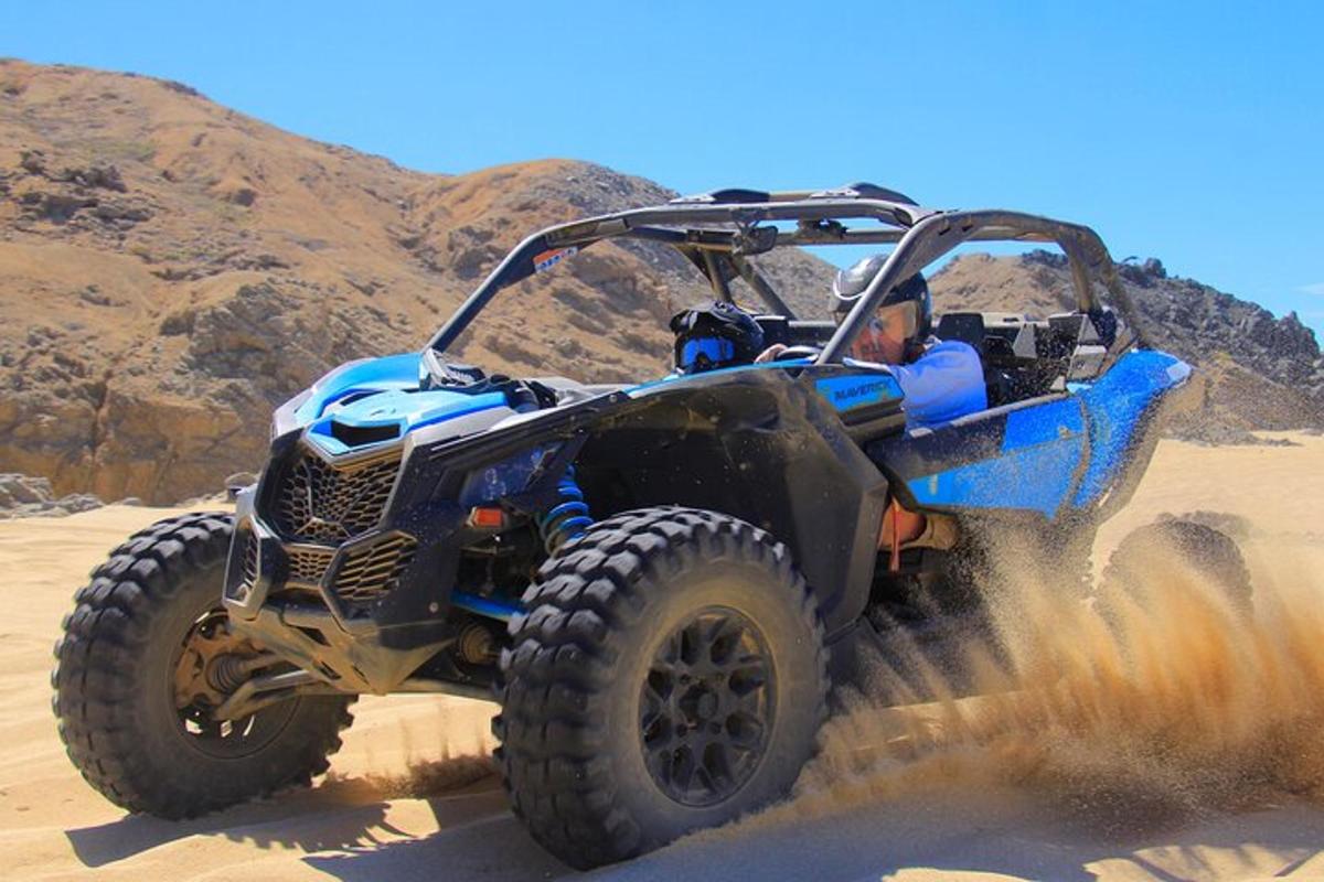 Un vehículo todo terreno azul circulando por la arena del desierto.