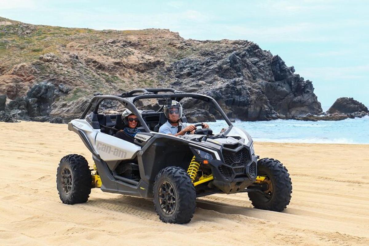 Dos personas viajando en un vehículo de cuatro ruedas en la playa