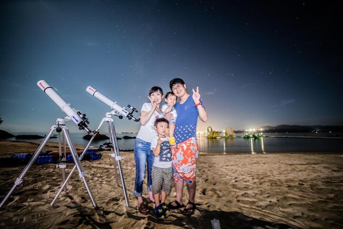 a family standing on the beach with a telescope