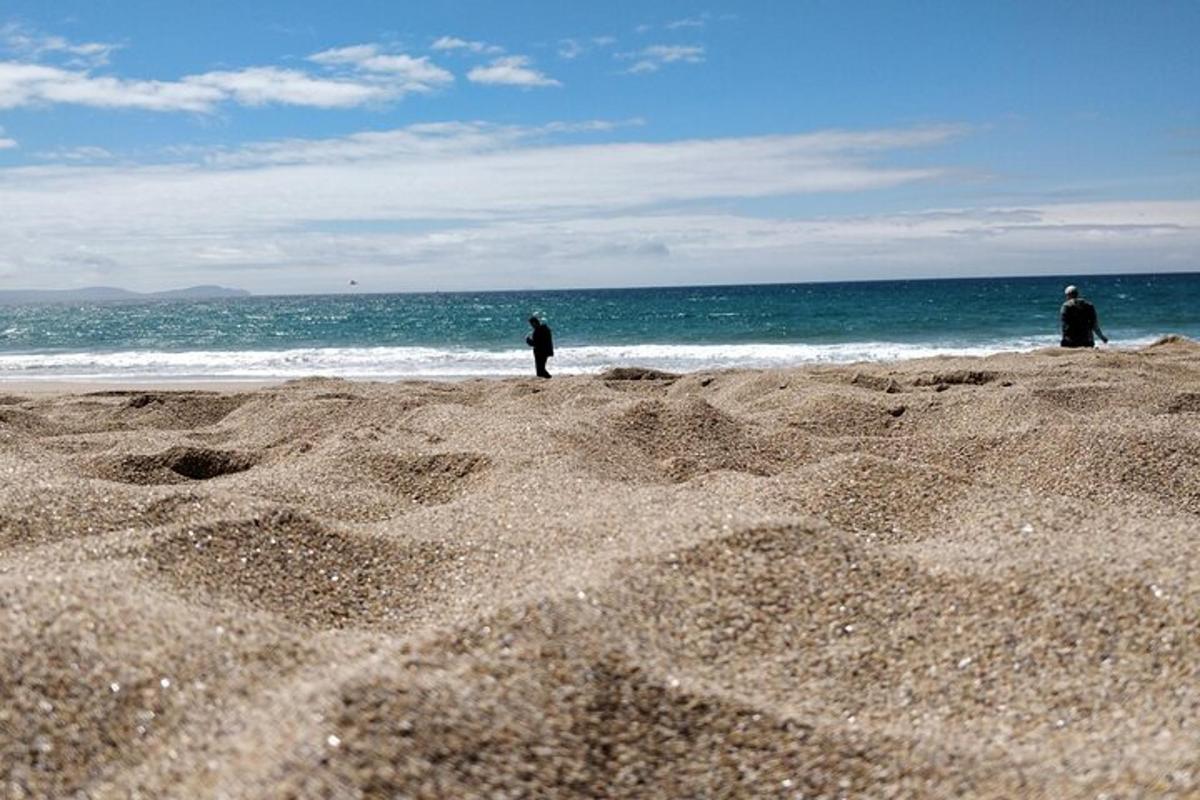 zwei Personen stehen an einem Strand in der Nähe des Ozeans
