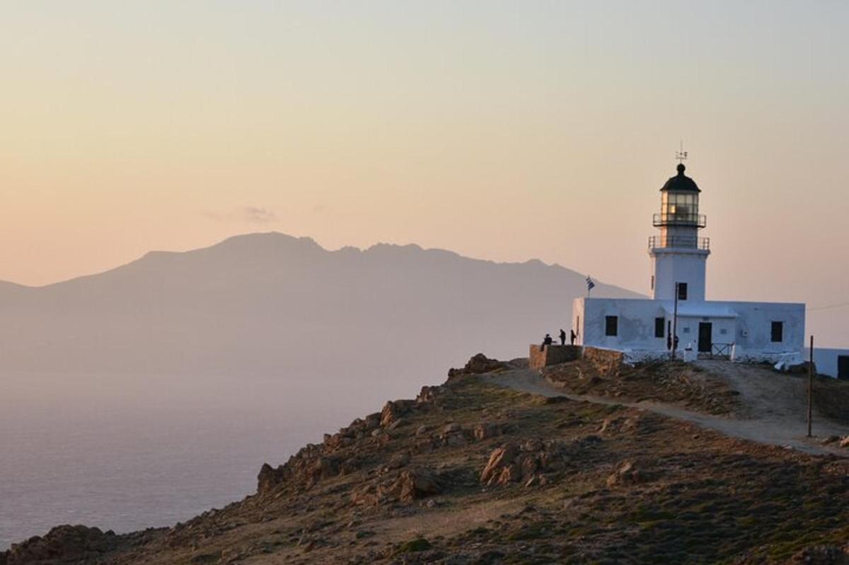 a lighthouse on top of a hill next to the ocean
