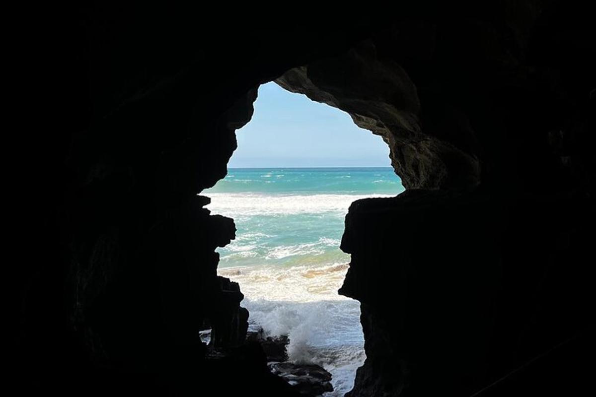 Una persona mirando desde una cueva hacia el océano.