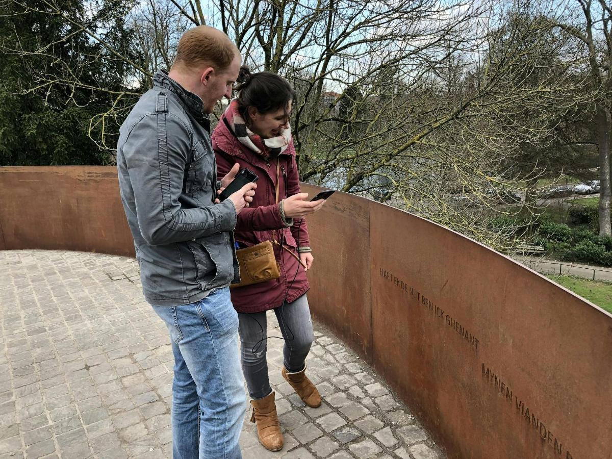 moški in ženska gledata v mobilni telefon