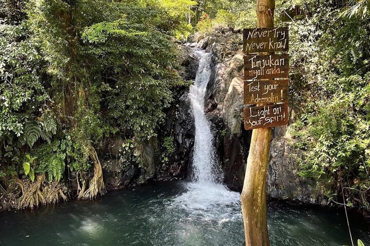 air terjun dengan papan tanda di hadapan sungai di sebelahnya