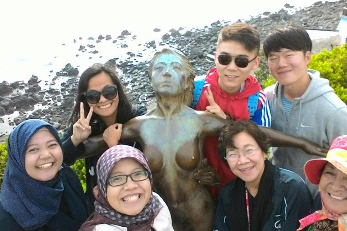 en gruppe mennesker som poserer foran en statue