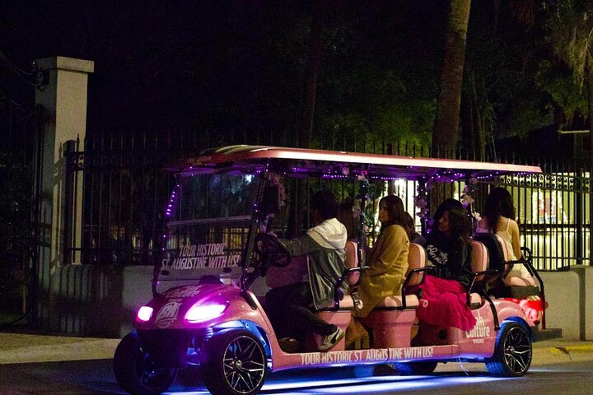 Un grupo de personas viajando en un carrito de golf por la noche.