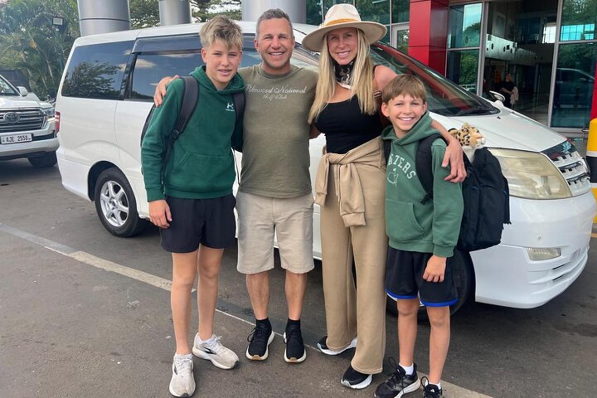 a man and a woman and two children standing next to a van