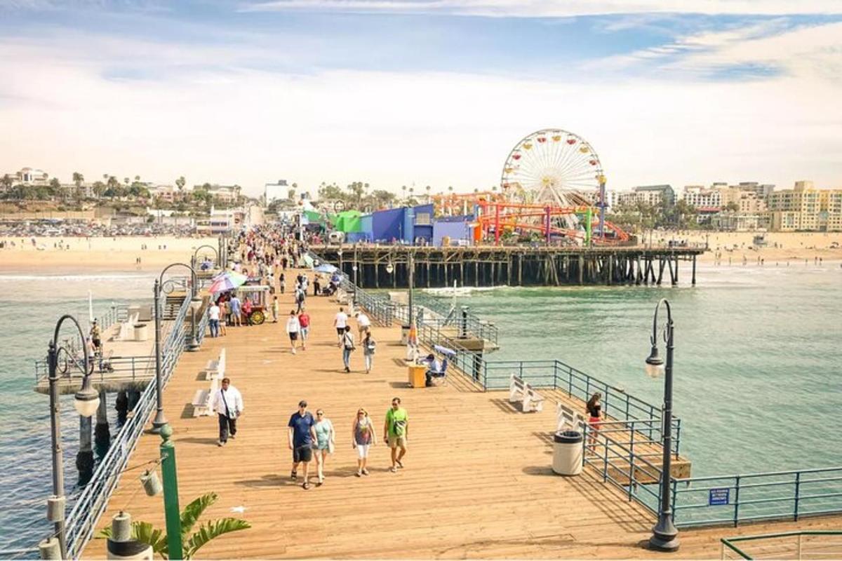 a group of people walking on a pier with a ferris wheel