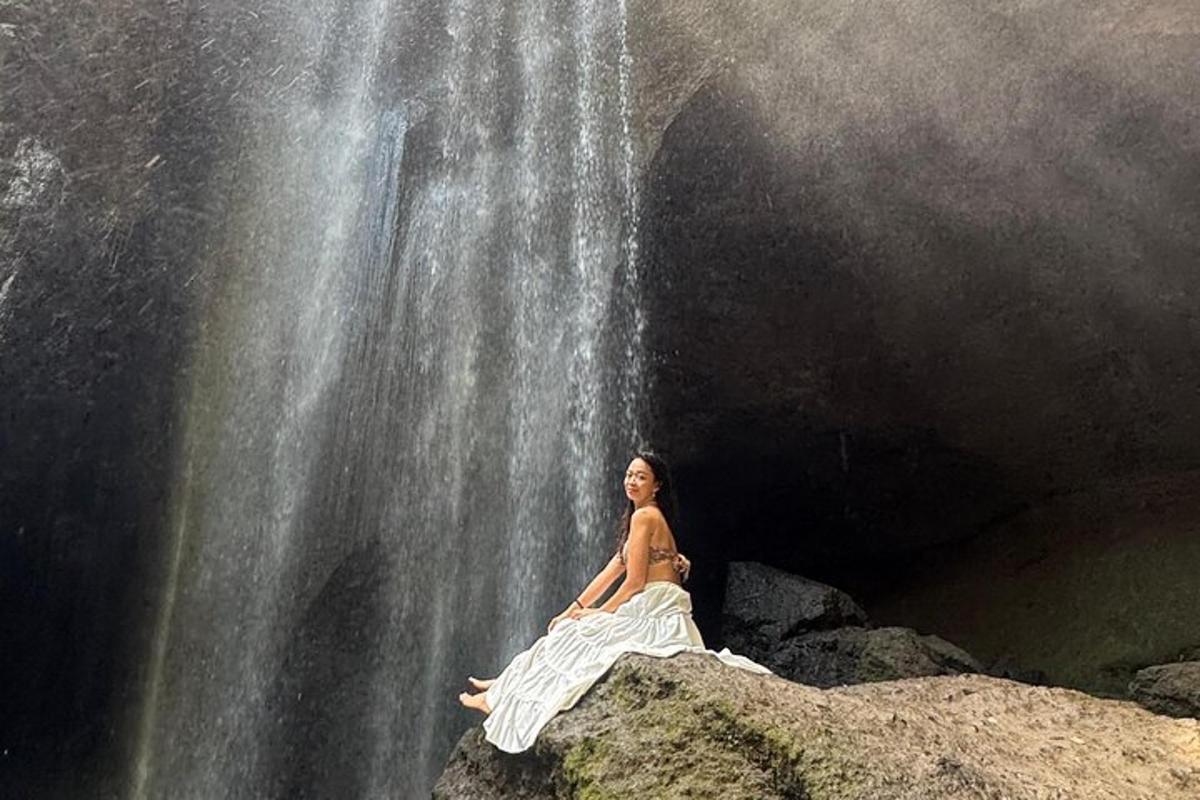 una donna seduta su una roccia di fronte a una cascata